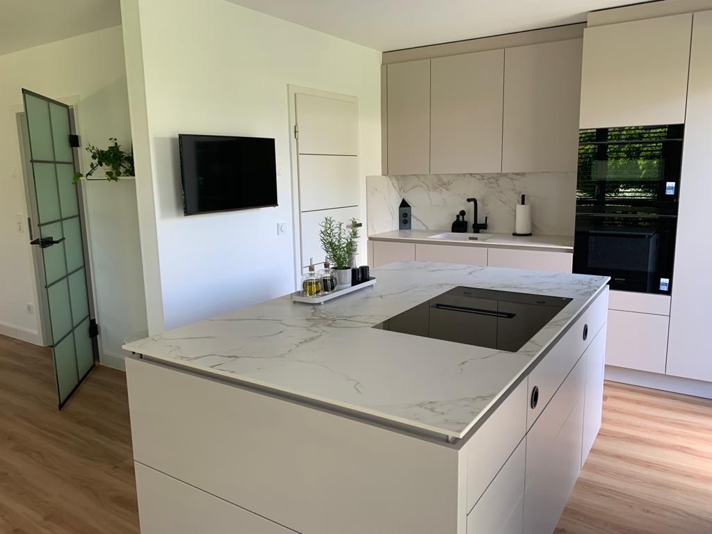 Moderne Häcker systemat Küche in Hamburg mit Kochinsel, Induktionskochfeld, heller Dekton-Arbeitsplatte und hochwertigen Einbaugeräten.