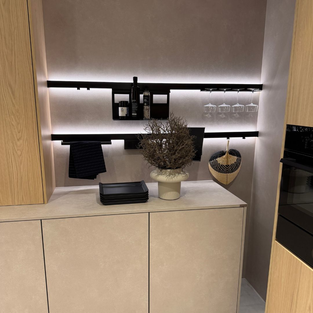 Moderne Küchenwand mit schwarzem Relingsystem und integrierter LED-Beleuchtung, flexibel bestückt mit Gläserhaltern, Ablagen und Haken – Beispiel für durchdachte Organisation und stilvolle Küchenplanung.