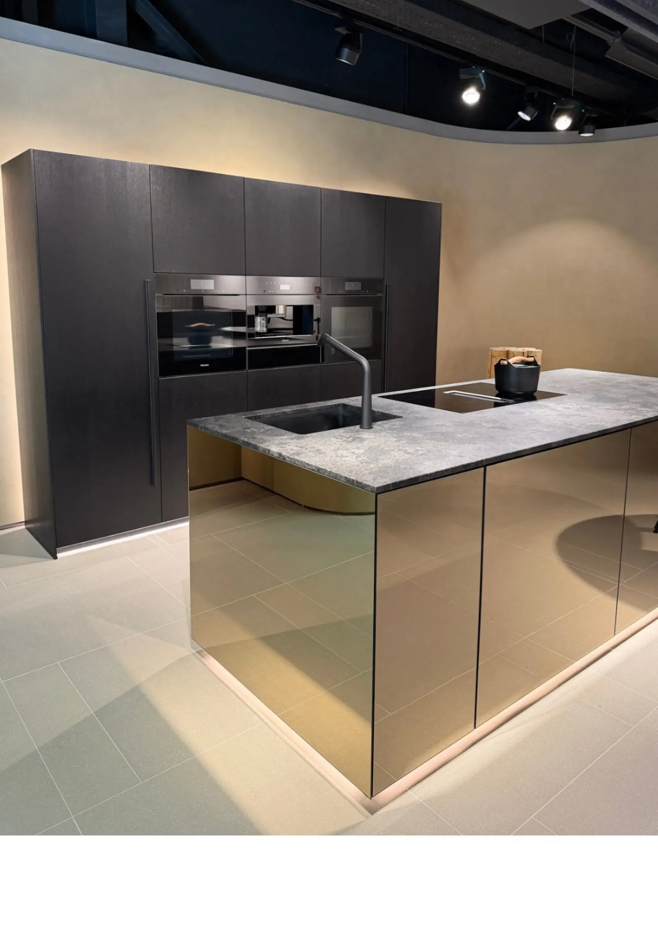 Moderne Küche mit dunklen Hochschränken und einer Kücheninsel in eleganten Spiegelfronten, kombiniert mit einer Stein-Arbeitsplatte und integrierter Spüle.